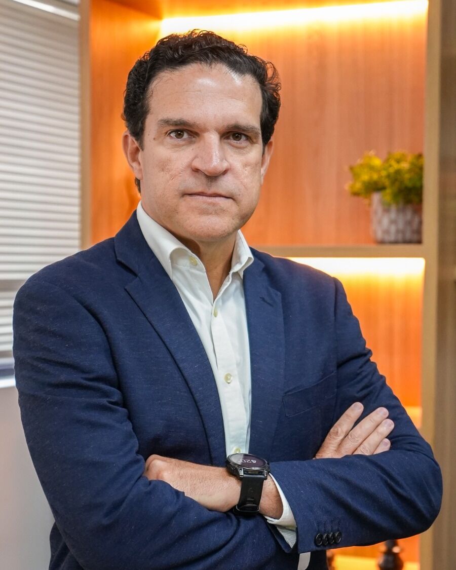 Retrato de Marcos Sampaio, de blazer azul-marinho e braços cruzados